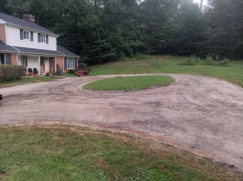 A large house with a dirt driveway in front of it.