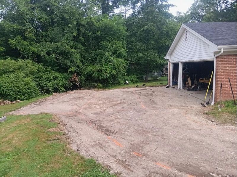 A dirt road leading to a garage with a brick building in the background.