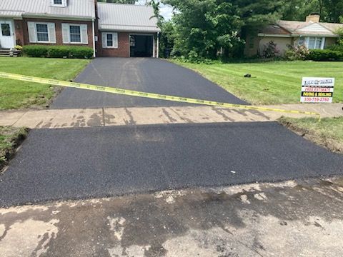 A brick house with a newly paved driveway in front of it.
