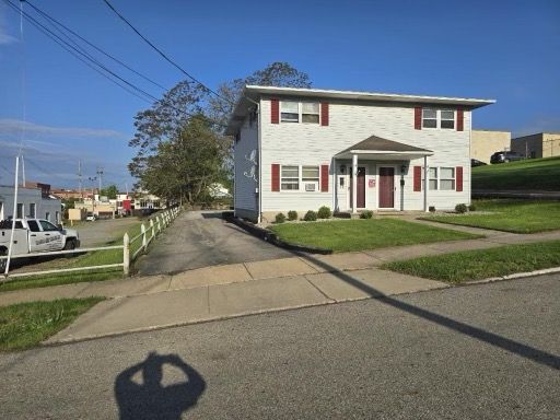 A white house with red shutters is on the side of the road.