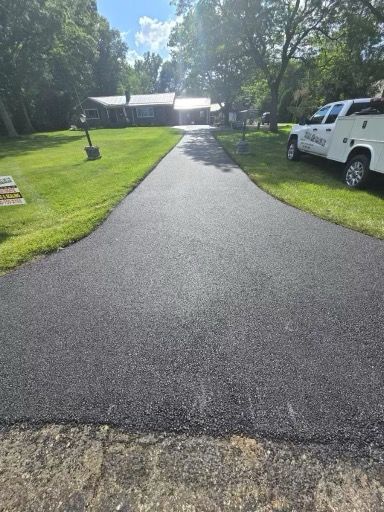 A driveway with a white truck parked on the side of it leading to a house.