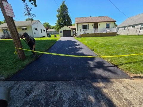 A man is working on a driveway in front of a house.