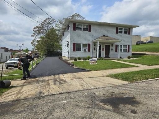 A man is paving a driveway in front of a house.