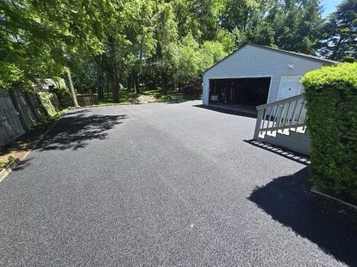 A driveway leading to a garage with a white building in the background.