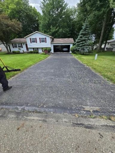 A man is paving a driveway in front of a house.