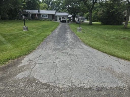 A driveway leading to a house with a lush green lawn.