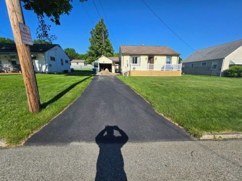 A person is taking a picture of a driveway leading to a house.