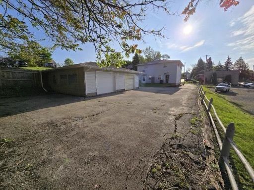 A parking lot with a garage and a house in the background.