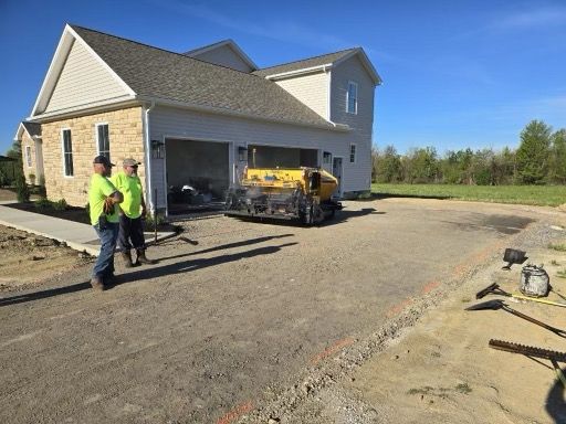 Two men are standing in front of a house with a yellow truck in the driveway.