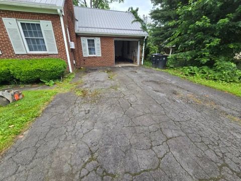 A driveway leading to a brick house with a garage.