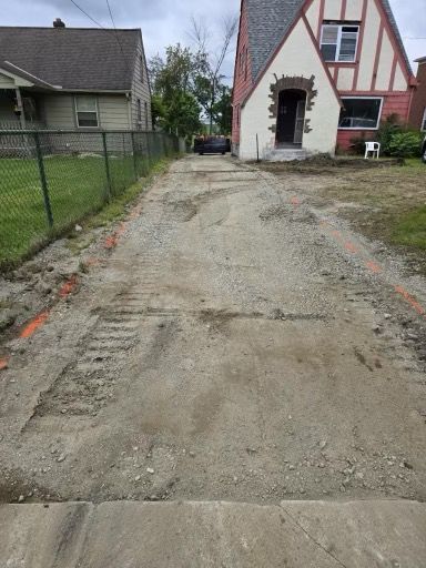 A dirt road leading to a house with a chain link fence.