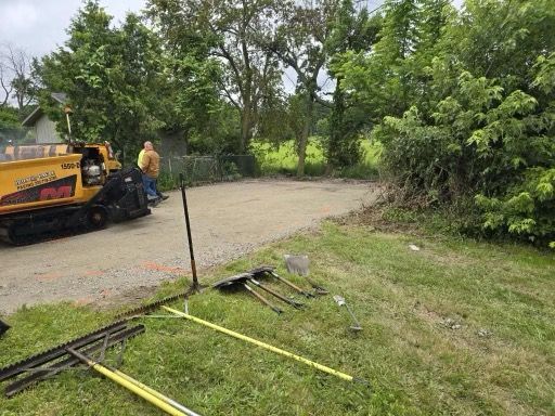 A yellow truck is parked on the side of the road next to a pile of tools.