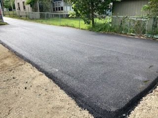 A close up of a newly paved road next to a house.
