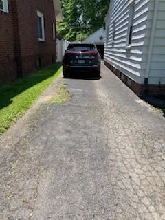 A car is parked in a driveway next to a house.