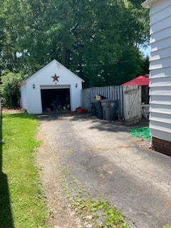A white garage with a star on it is in the backyard of a house.