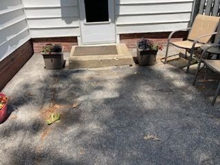 A patio with chairs and potted plants in front of a house.