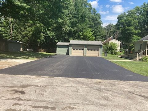 A driveway with a garage and a house in the background.