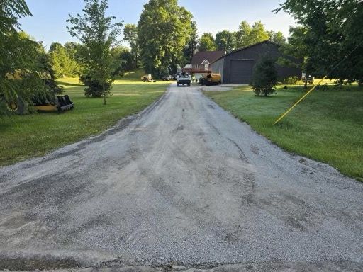 A dirt road leading to a house with a garage