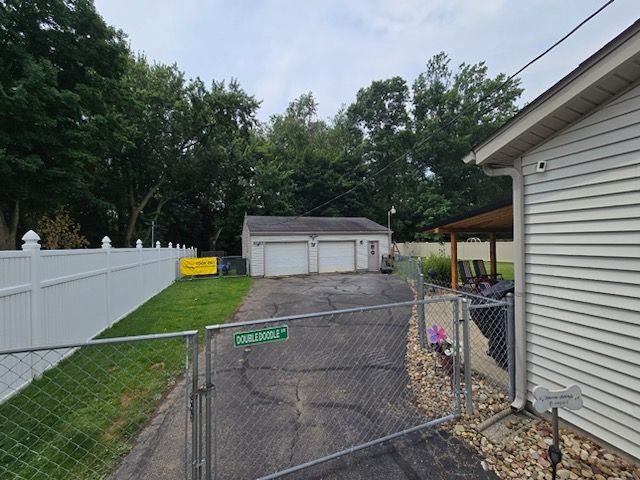 A chain link fence surrounds a driveway leading to a garage and a house.