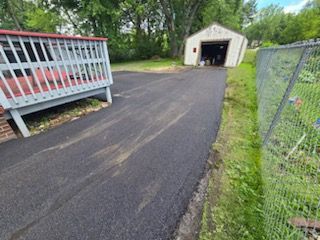 A driveway with a fence and a garage in the background.