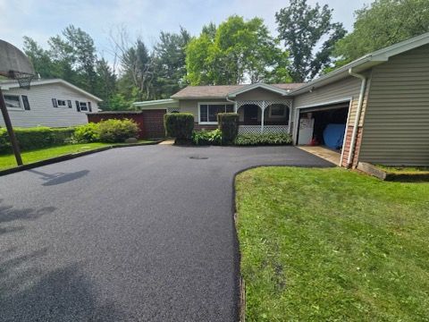 A driveway leading to a house with a basketball hoop in the background.