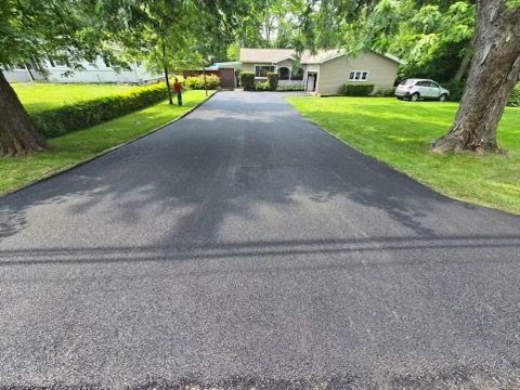 A driveway leading to a house with a car parked on the side of it.