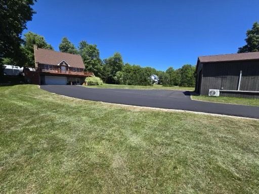 A driveway leading to a house with a barn in the background
