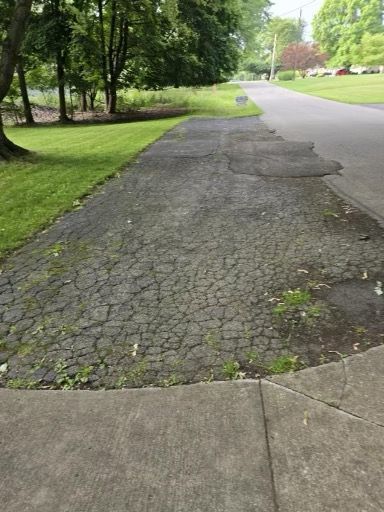 A sidewalk leading to a road with trees on the side of it.