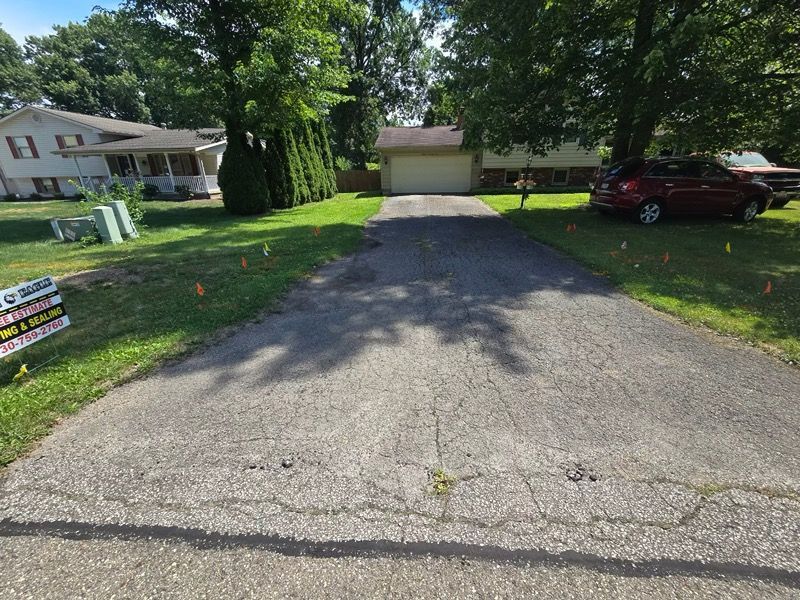 A red car is parked in a driveway next to a house.