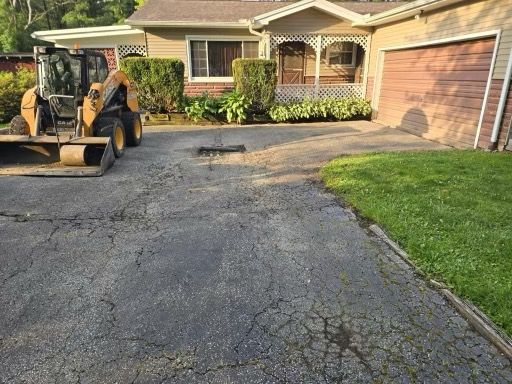 A bulldozer is parked in a driveway in front of a house.