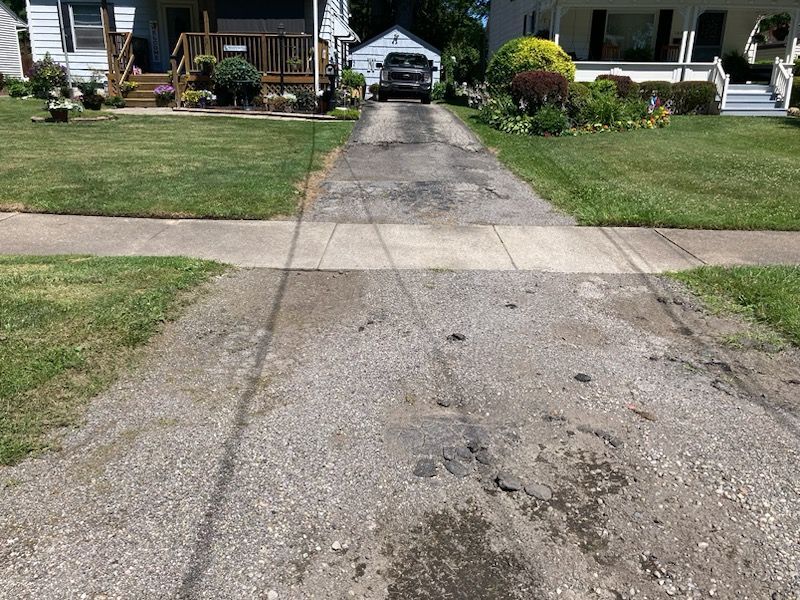 A car is driving down a driveway next to a house.