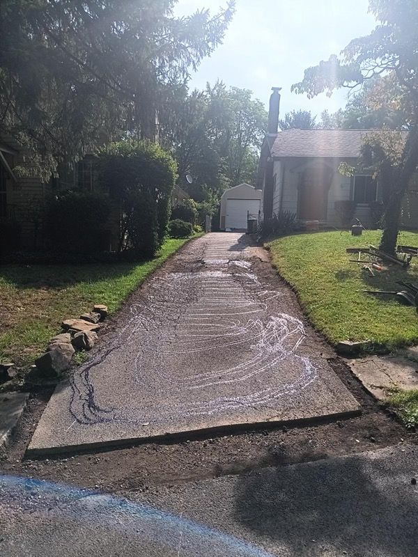 A concrete driveway leading to a house on a sunny day.