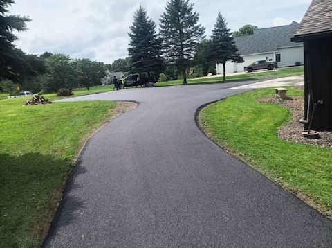 A asphalt driveway leading to a house in a residential neighborhood.