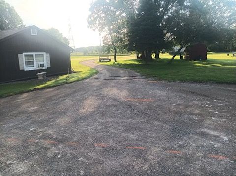 A dirt road leading to a house in the middle of a field.