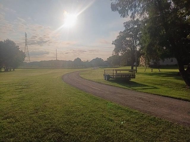 A trailer is parked on the side of a dirt road in a grassy field.
