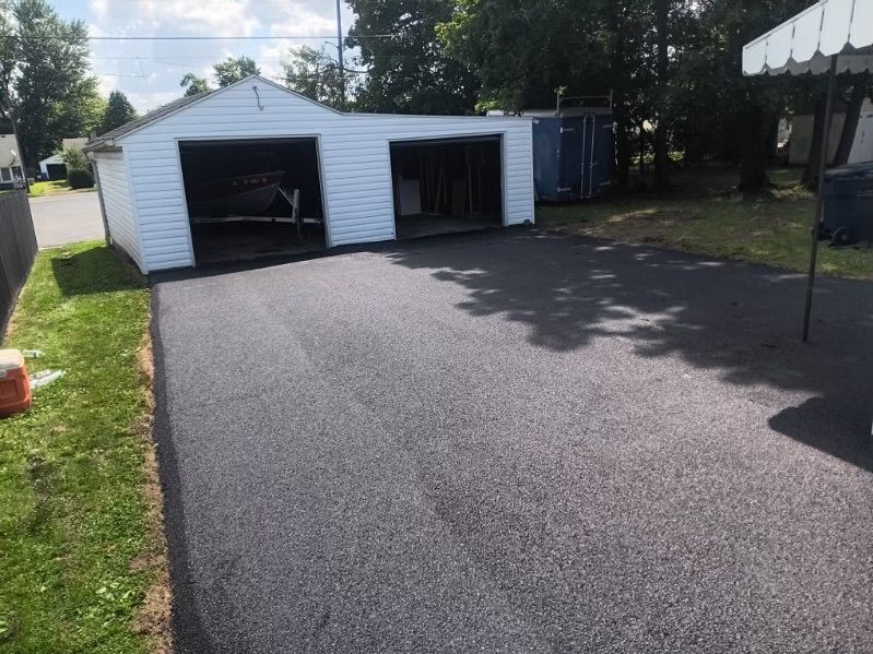A driveway with a garage in the background and a tent in the foreground.