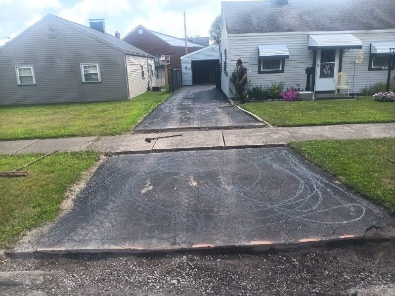 A man is standing in the middle of a driveway next to a house.