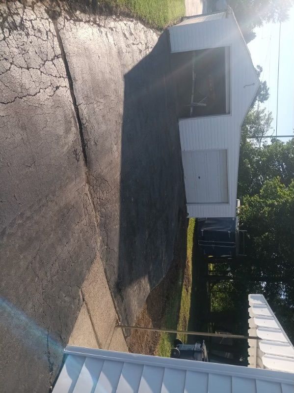 A white house is sitting in the middle of a driveway next to a fence.