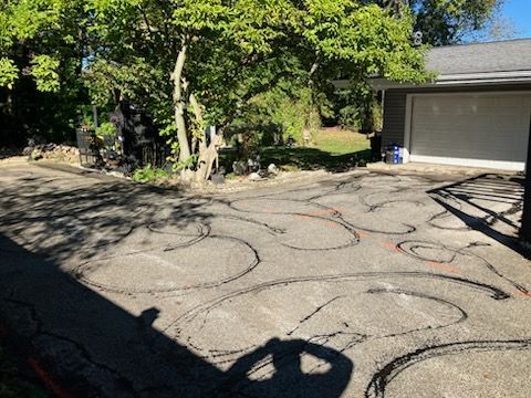 Driveway with black and orange lines; garage and trees in background.