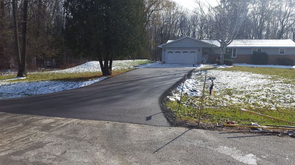 A driveway leading to a house with snow on the ground