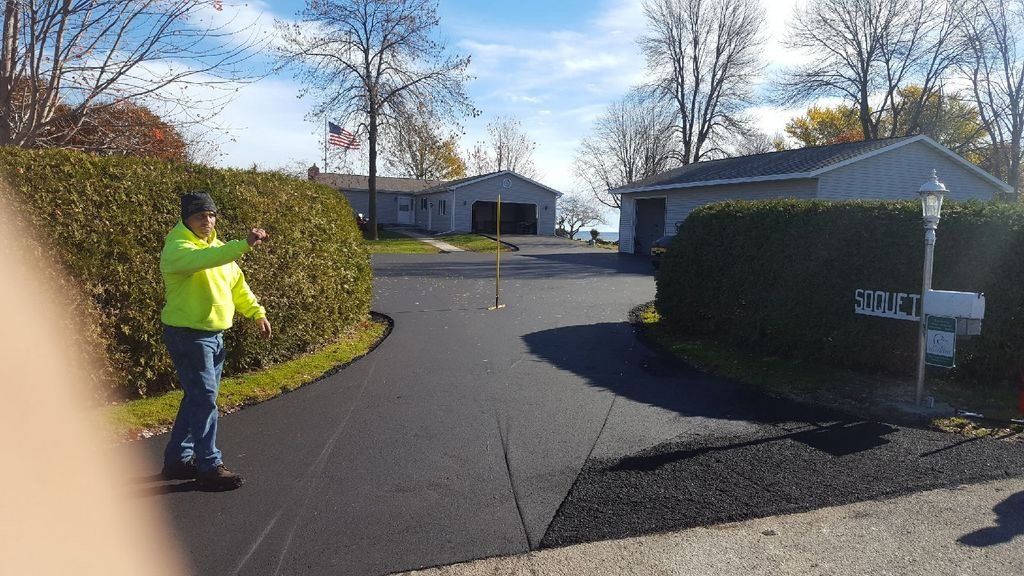 A man in a yellow jacket is standing on a driveway next to a mailbox.