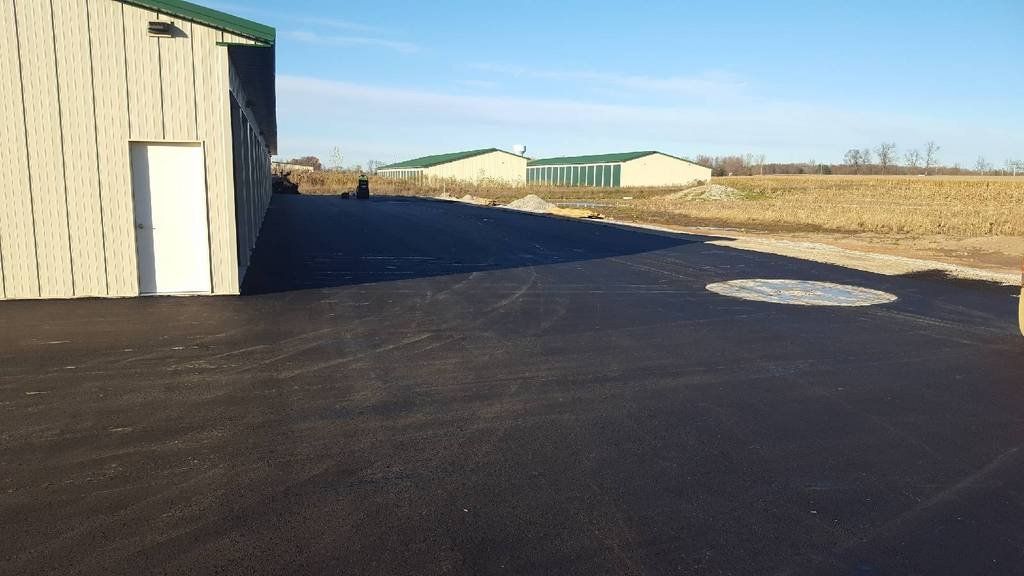 A building with a green roof and a white door is in the middle of a field.