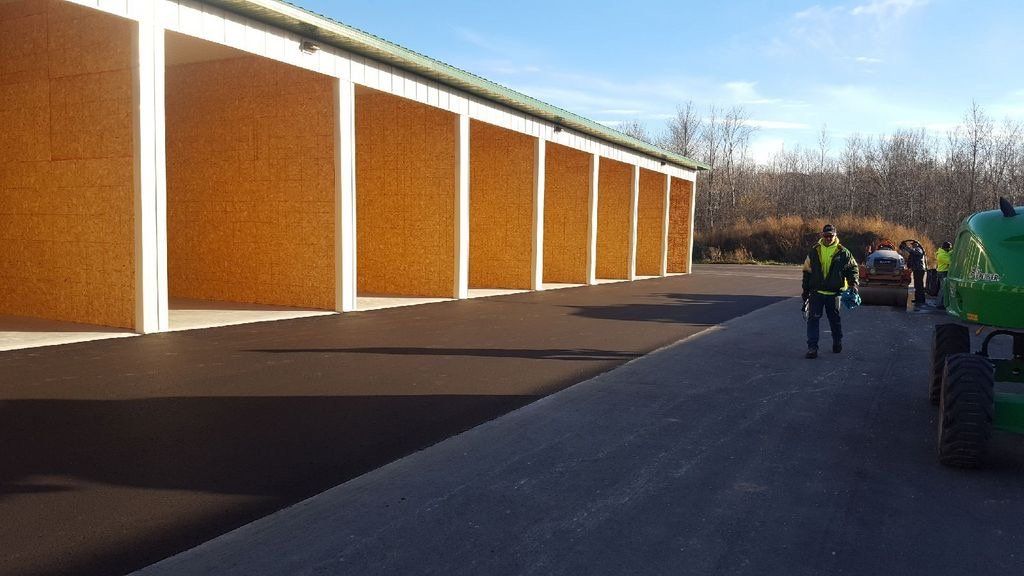 A man in a yellow vest is standing in front of a building.