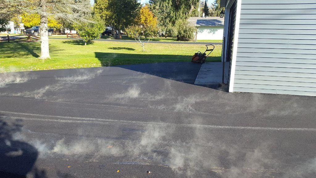 A lawn mower is parked in a driveway next to a garage.