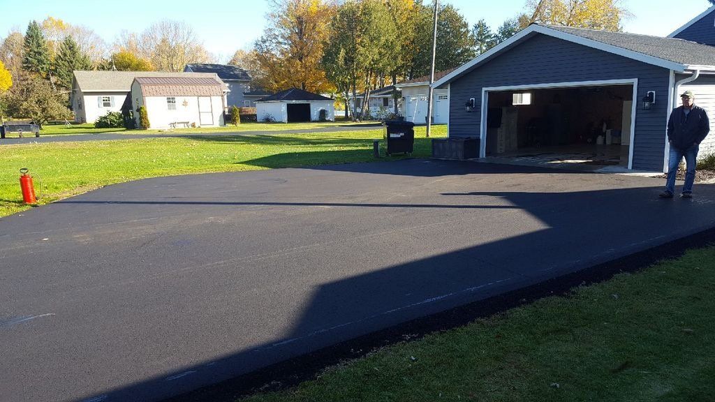 A man is standing in a driveway in front of a garage