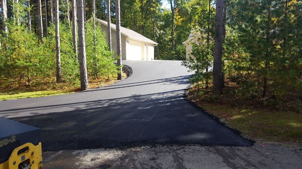 A driveway leading to a house in the woods.