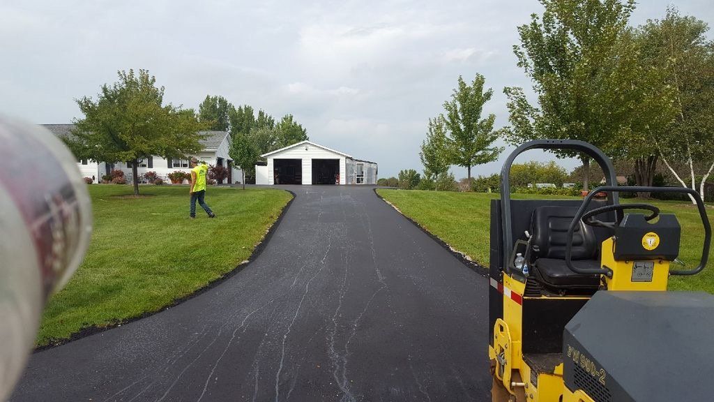 A man walking down a driveway next to a roller