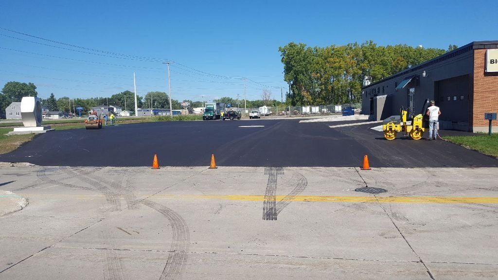 A parking lot is being paved in front of a building