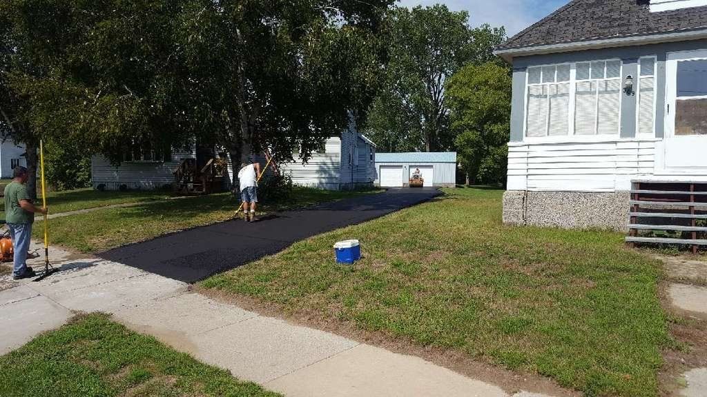 A man is standing on a sidewalk in front of a house.