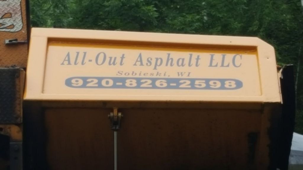 A yellow sign that says all-out asphalt llc on it